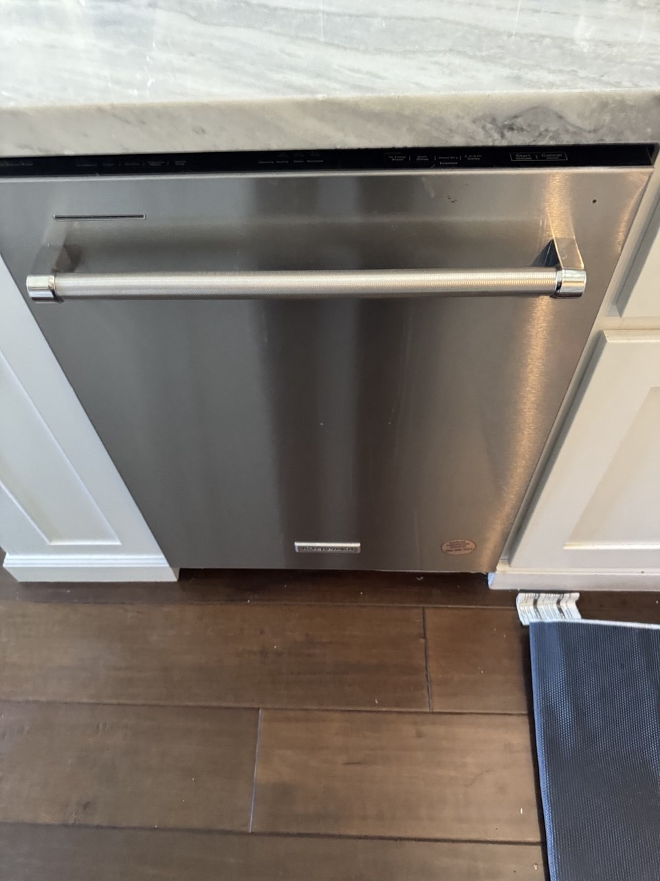 Built-in stainless steel KitchenAid dishwasher under a stone countertop